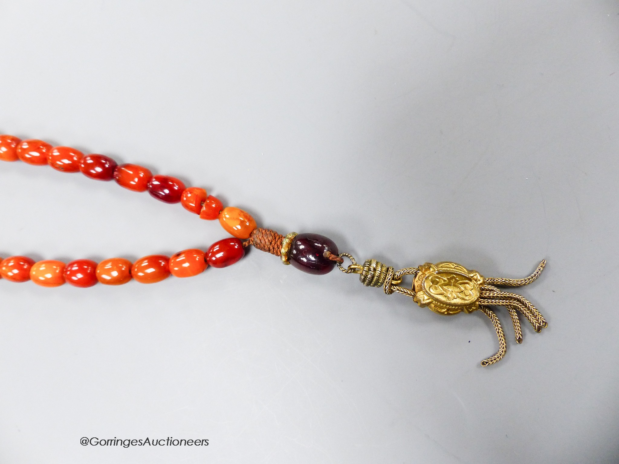 A single strand amber bead necklace, with gilt metal pendant, 36cm, gross weight 12 grams.